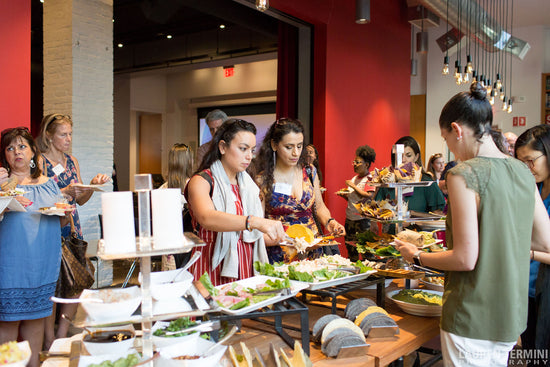 Individuals enjoying a meal from a buffet table, serving themselves from a variety of delectable food options