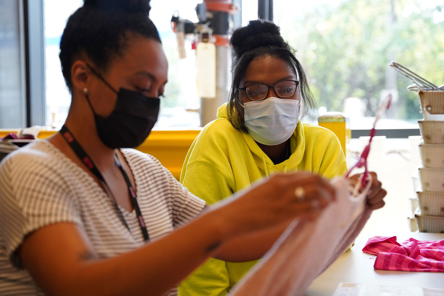 Two women diligently collaborating on a project while wearing protective face masks
