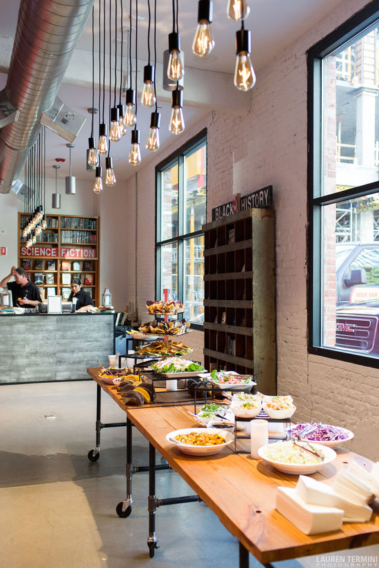 A restaurant-style setting is created in a bookstore for a special event, with a beautifully decorated, lengthy table featuring a variety of food options