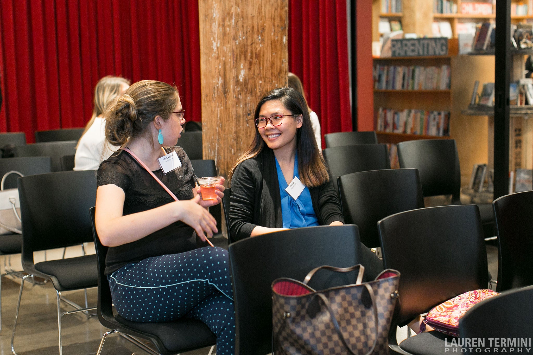 Two women engaged in conversation while seated in chairs, displaying attentive body language and engaged facial expressions