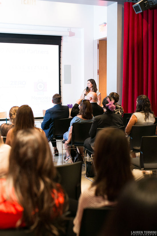 A professional woman confidently delivering a presentation to a attentive audience in a well-lit conference room