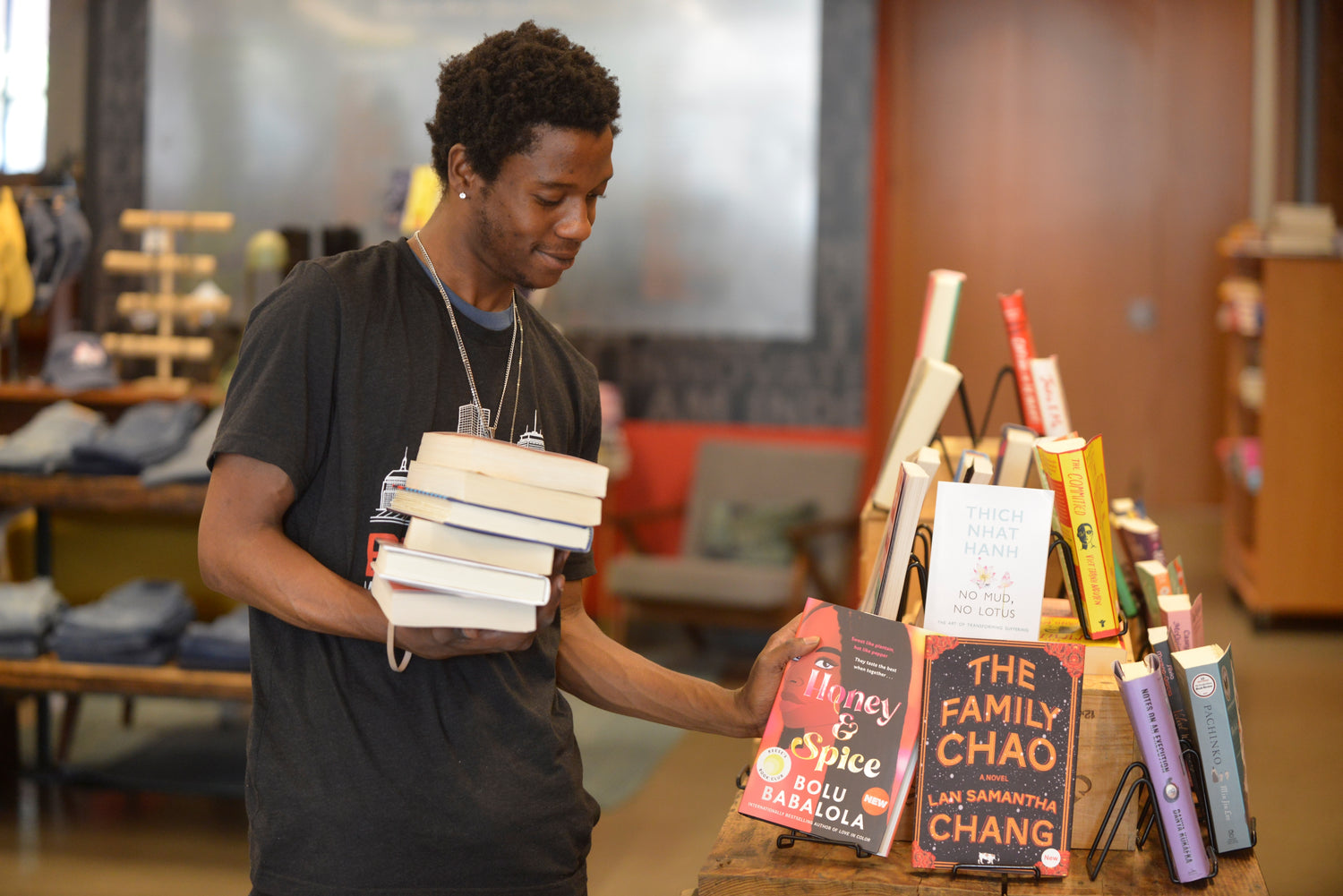 A youth from More than Words stands before a bookshelf filled with books, showcasing a diverse collection of literary works
