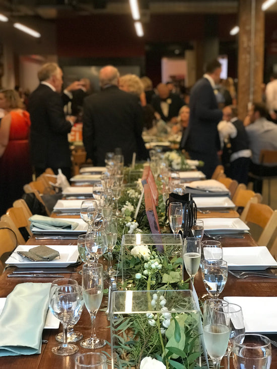 An extensive table hosting a large gathering of people, engaged in lively discussions and enjoying a meal together